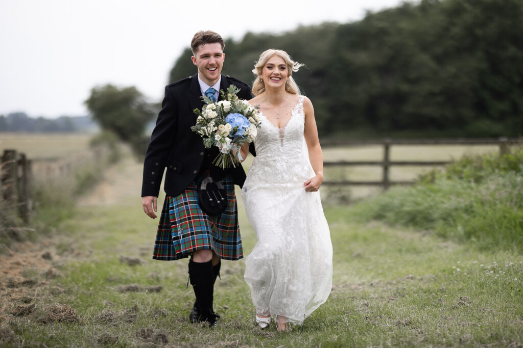 couple walking in the fields at Bachilton Barn wedding