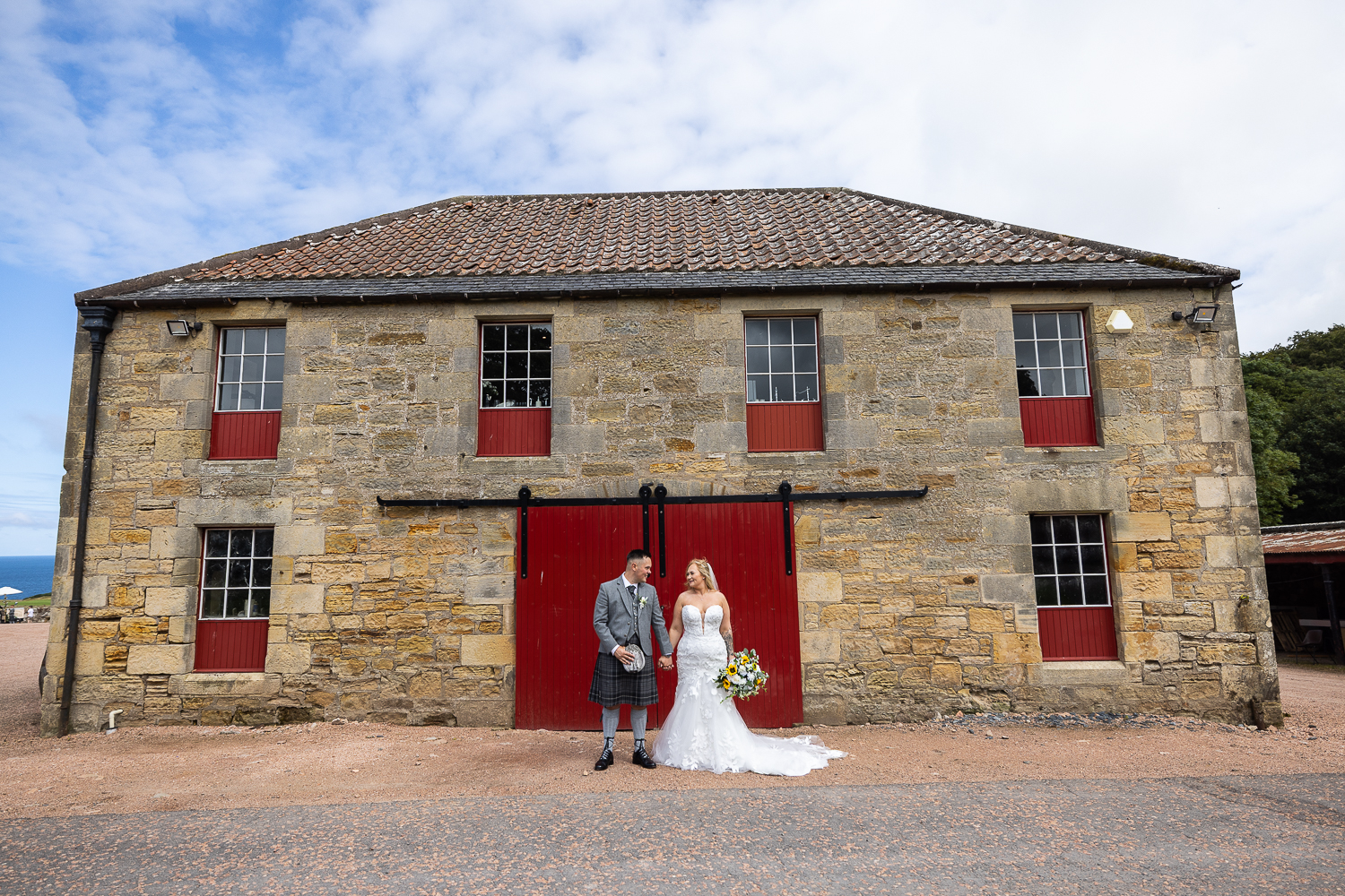 kinkell byre bride and groom portrait against the red barn doors