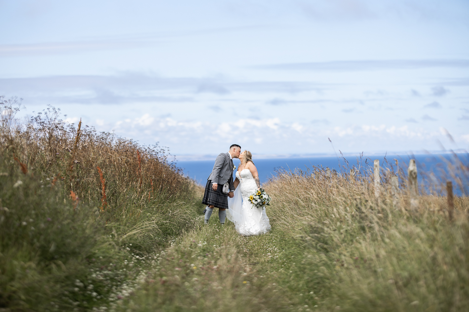 kinkell byre bride and groom portrait kissing in a track with the sea in the background