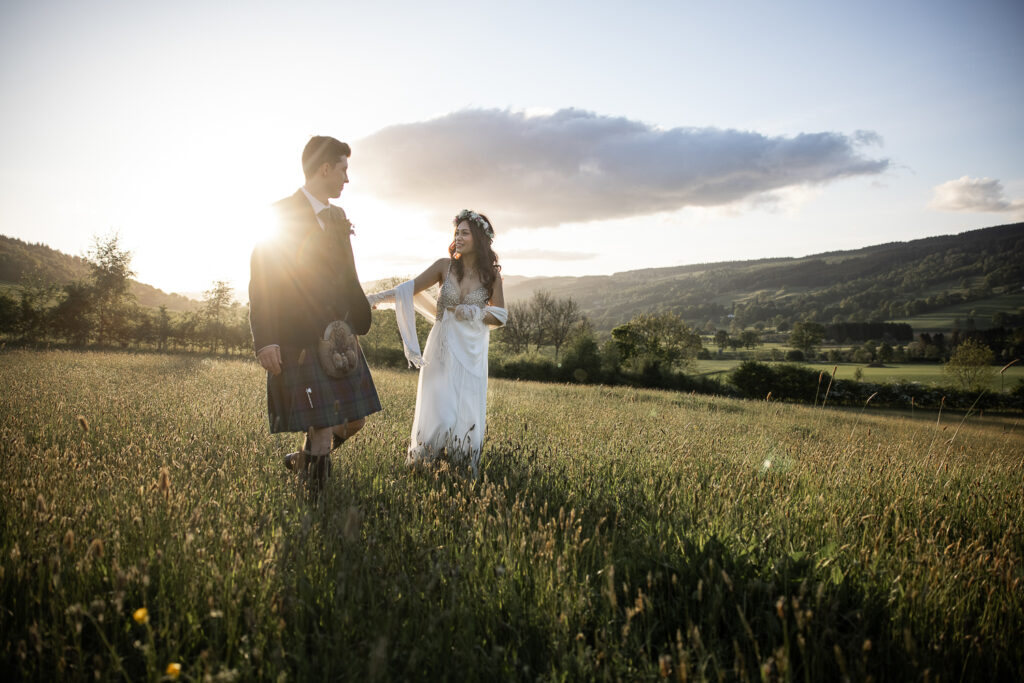 couple walking in the evening sunshine looking at each other in a field at Ballintaggart