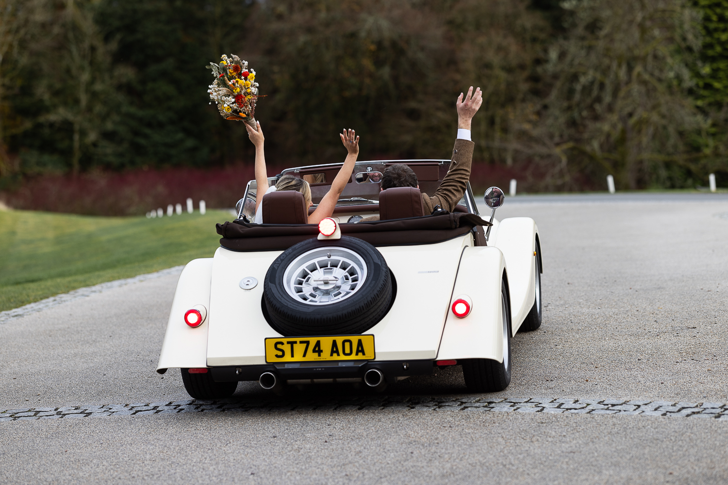 wide angle of couple portrait leaving in the vintage car