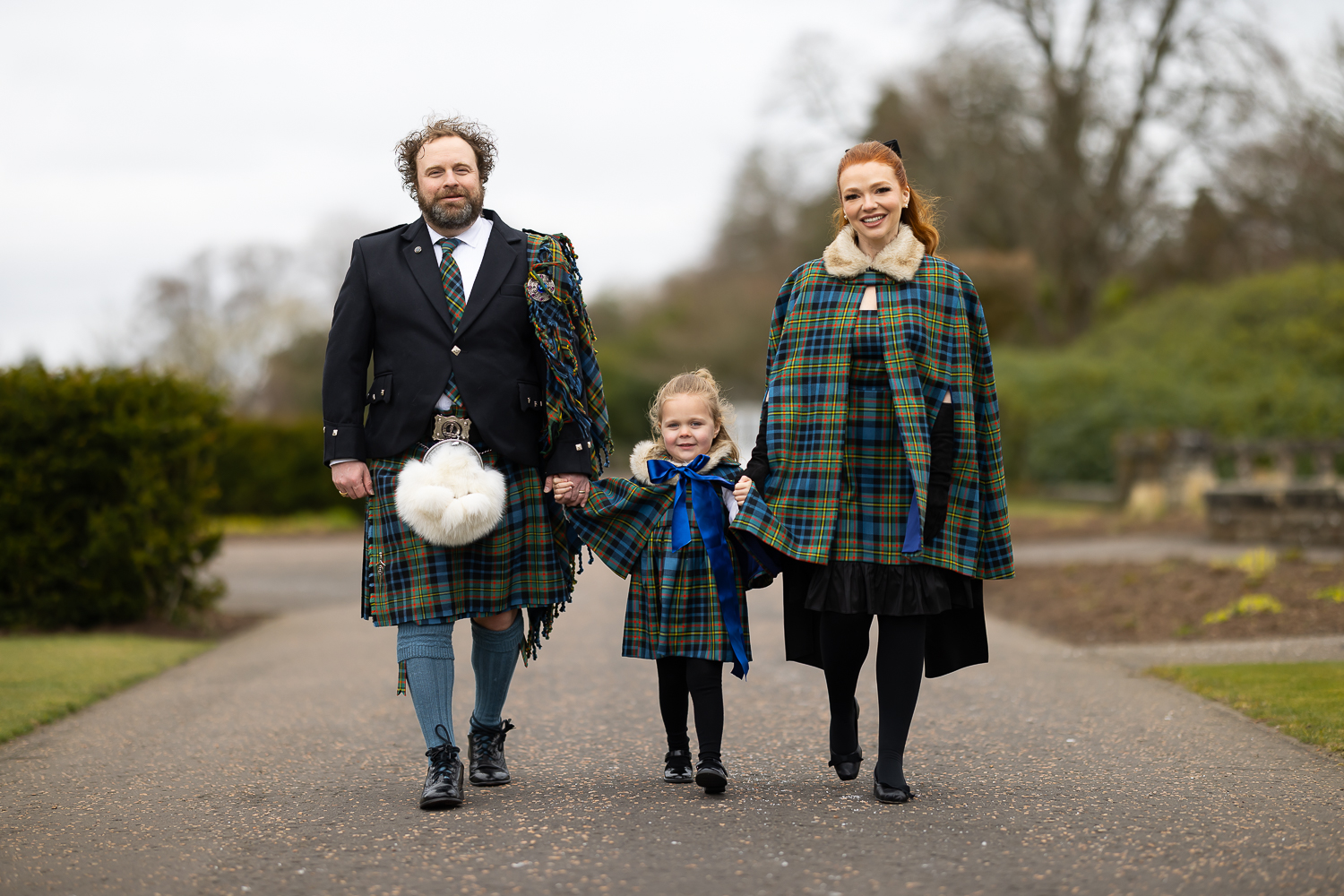 family dressed in tartan walking down a path at gleneagles hotel