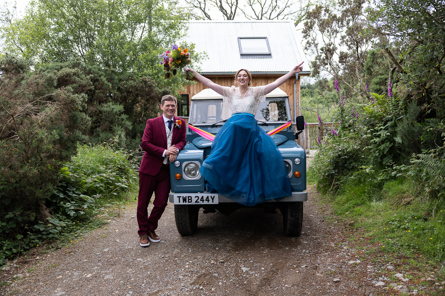 Bride standing on the front of a vintage Land Rover with the groom at Comrie Croft.